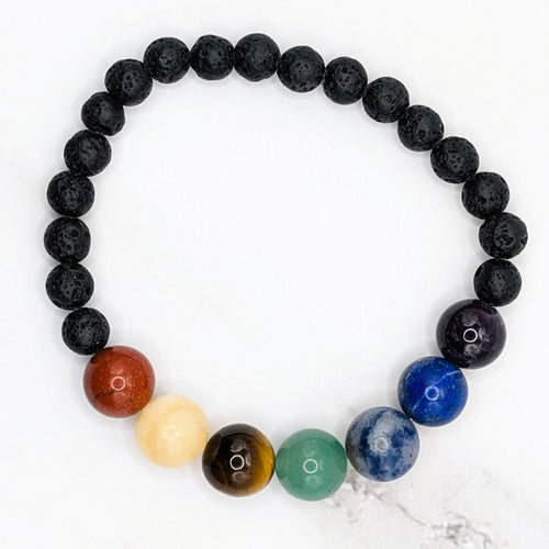 Handmade chakra bead stretch bracelet with lava beads, flat lay on marble