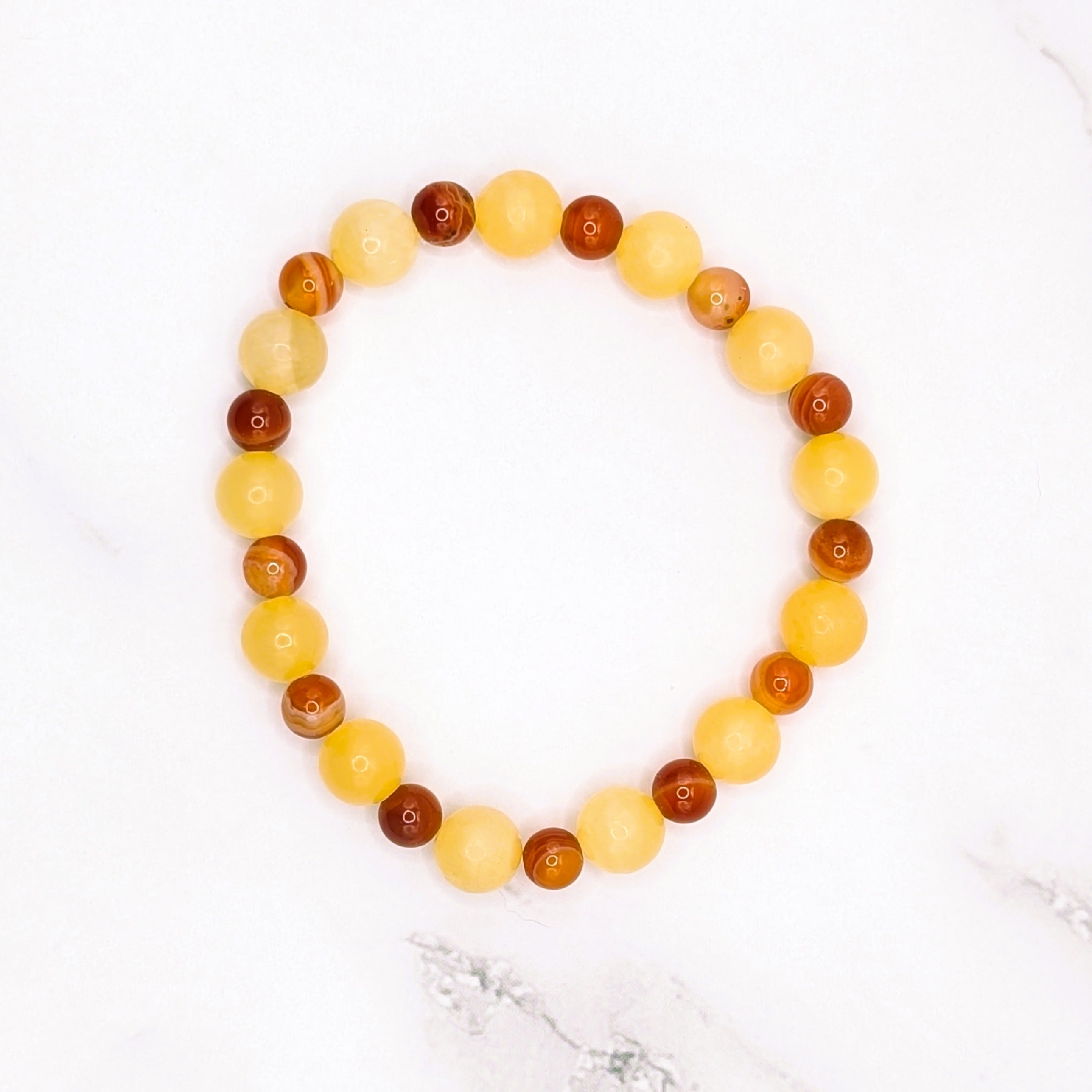Handmade honey stone and carnelian stretch bracelet, flat lay on marble