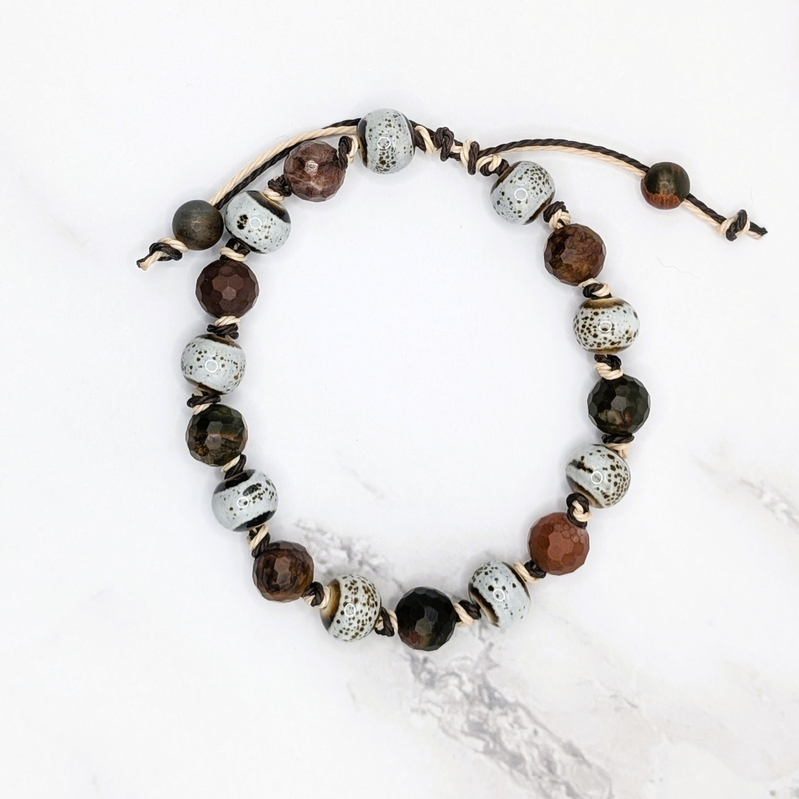 Handmade birch speckled porcelain and red jasper knotted bracelet, flat lay