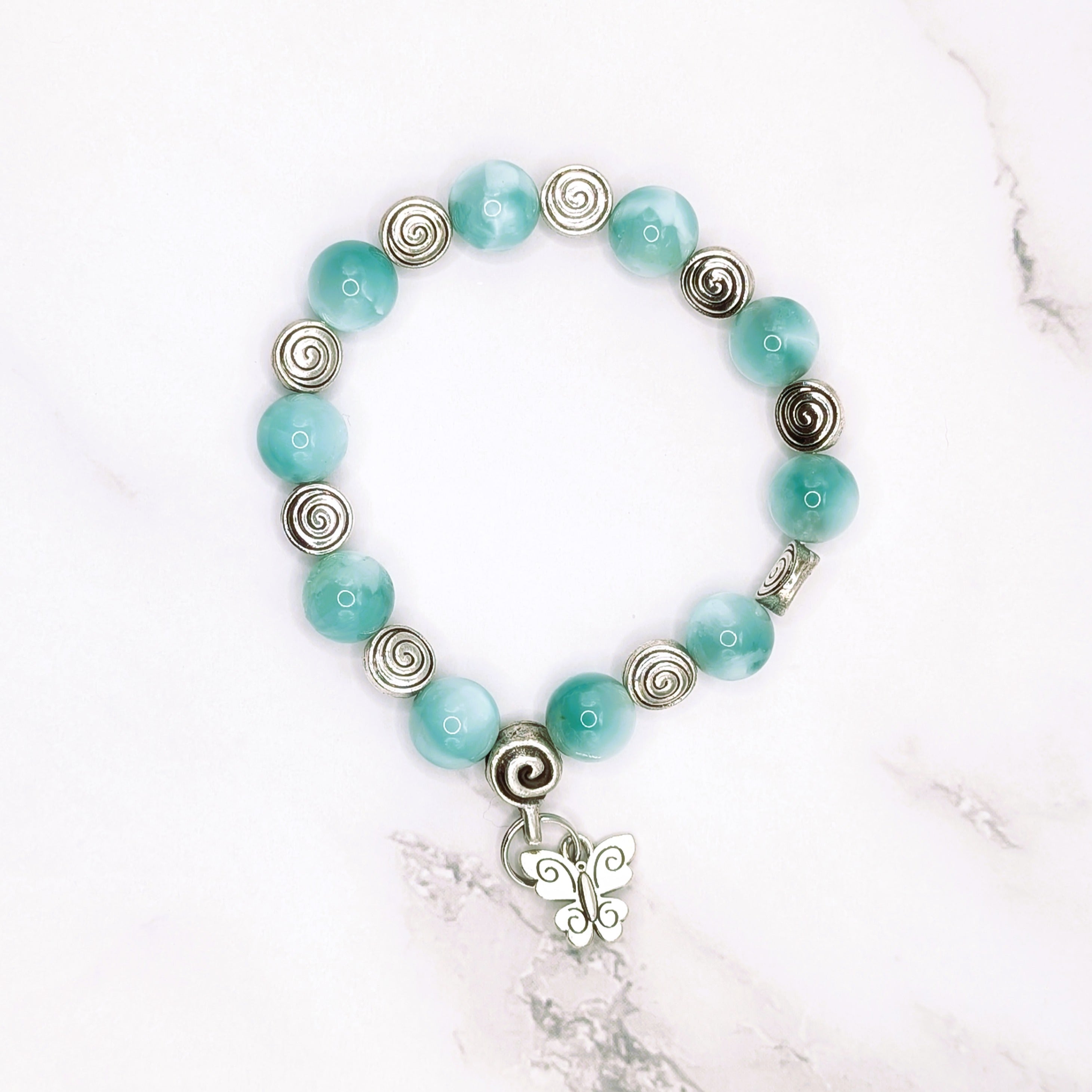 Handmade green pectolite stretch bracelet with butterfly charm, flat lay
