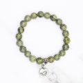 Handmade Russian serpentine stretch bracelet with bird charm, flat lay on marble