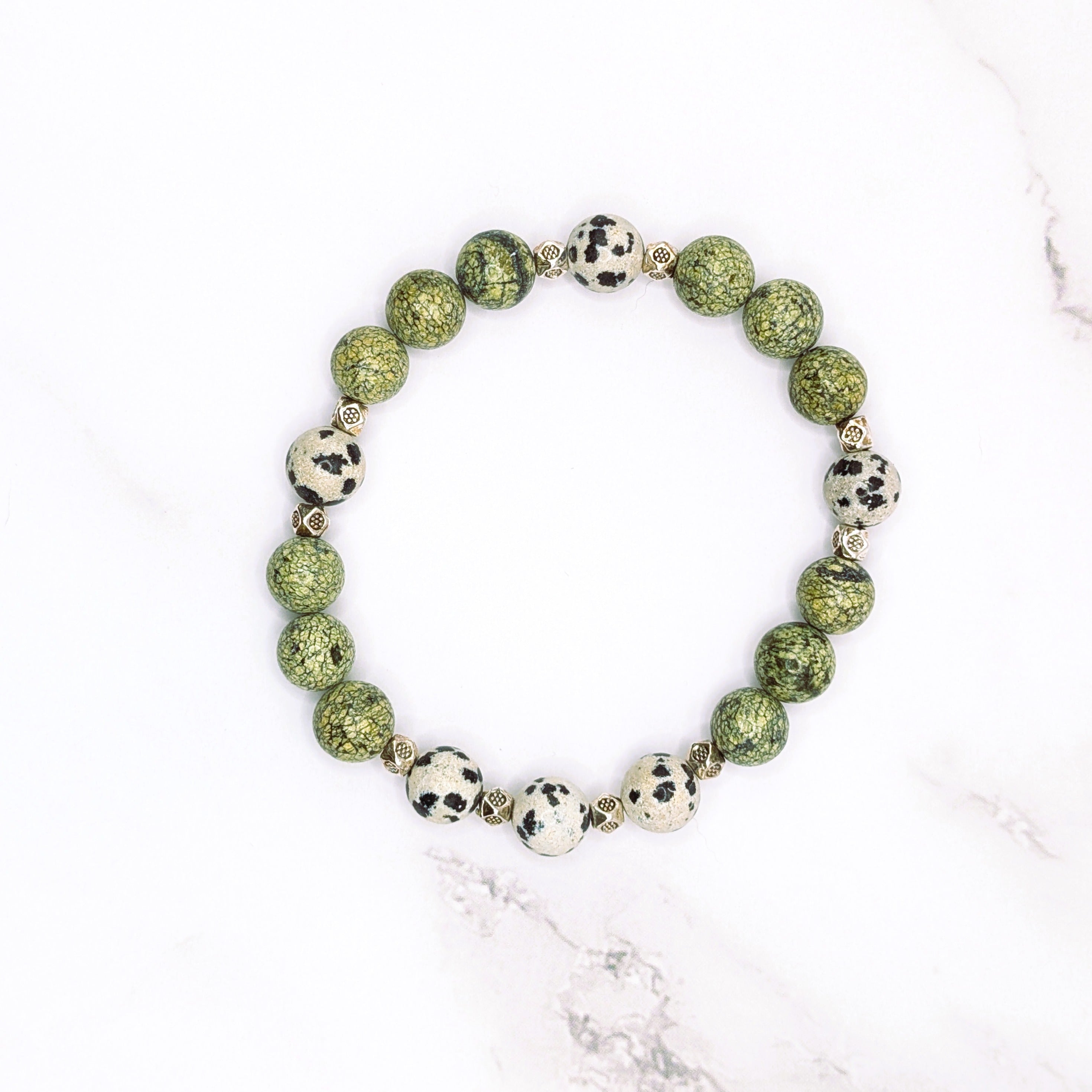 Handmade Russian serpentine and Dalmatian jasper stretch bracelet, flat lay on marble